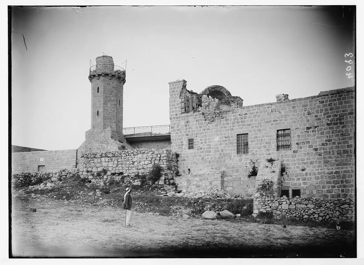 צריח עגול לצד בניין אבן, שגגו וחלק מקירותיו נפלו.