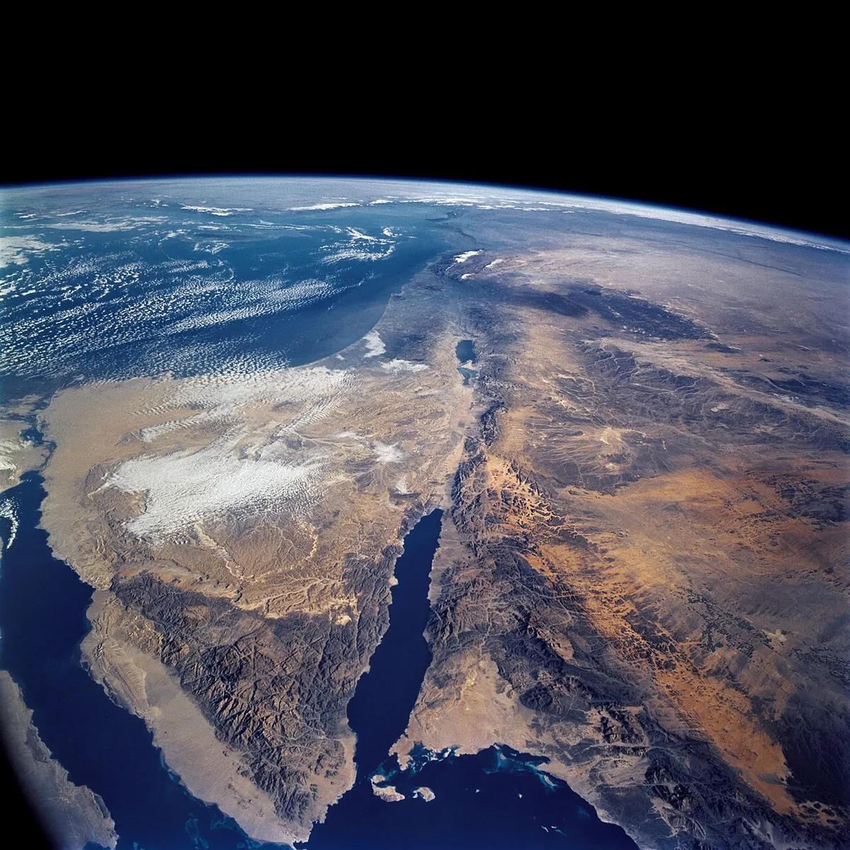 צילום מהחלל: משולש חצי האי סיני בין שני מפרצים כחולים, ומעליו פס צר של מים, ים המלח.